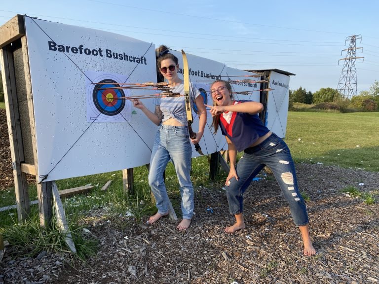 Two barefoot women standing happily in front of their bullseye
